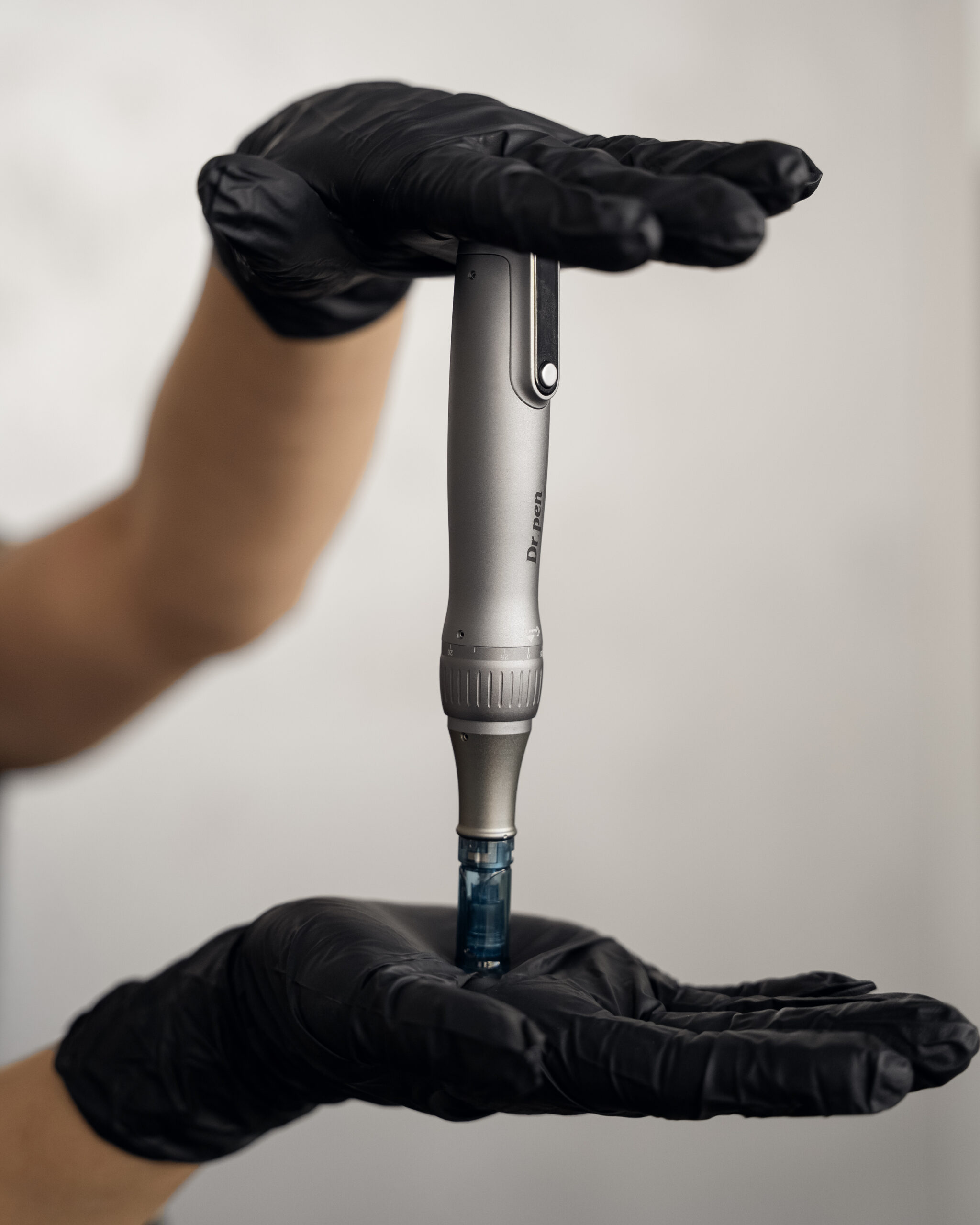 A handheld skin-care device held between gloved hands.