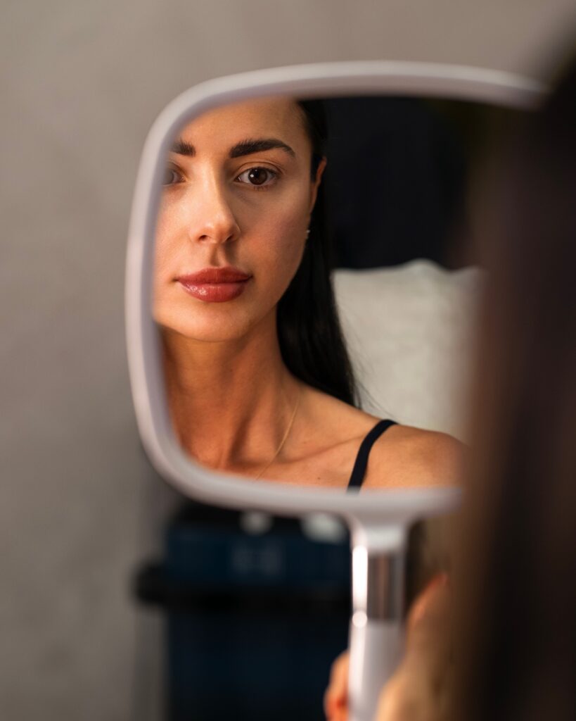 A woman’s face reflected in a handheld mirror.