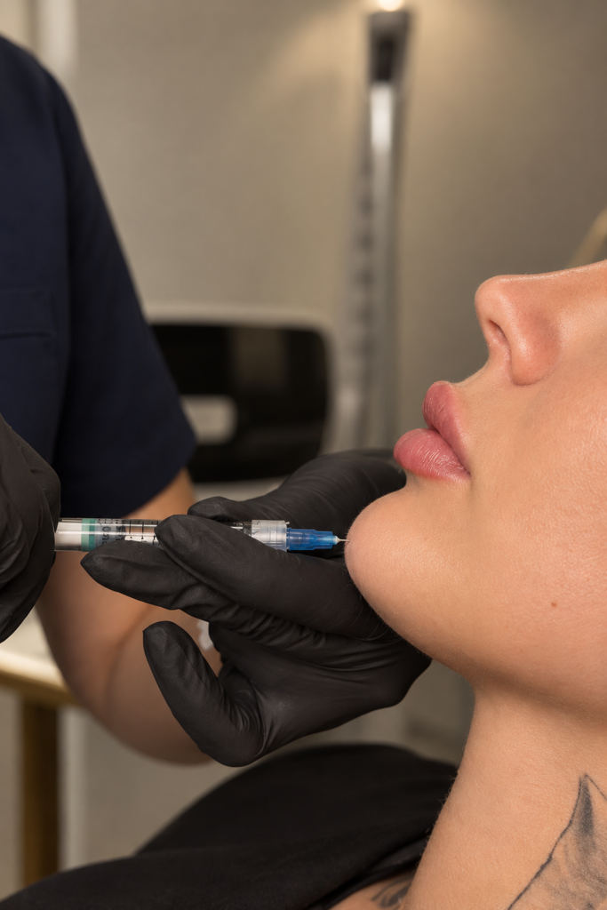 Gloved hands holding a syringe at the chin.